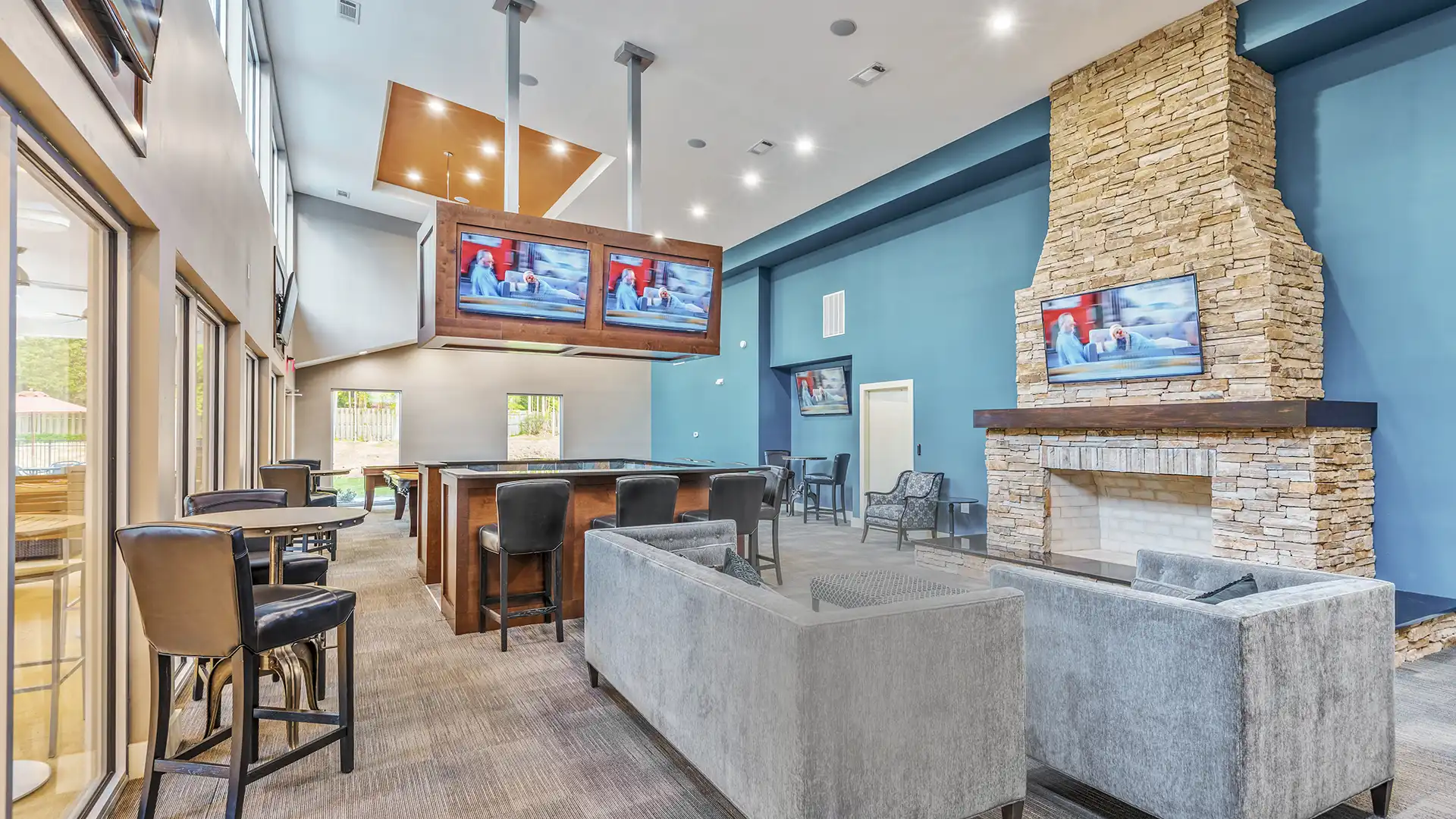 Clubhouse with large fireplace, couches, hightop seating, and several TVs.