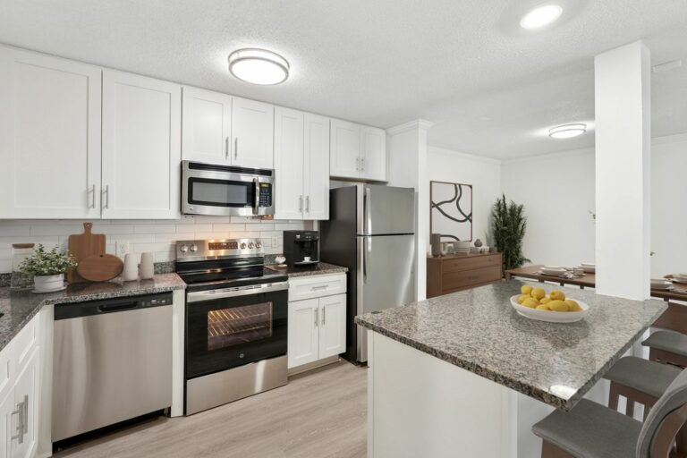 Modern kitchen with sleek stainless steel appliances, granite countertops, and elegant white cabinetry adjacent to a stylish dining area.