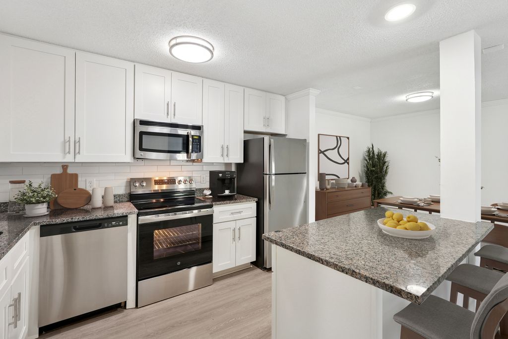 Modern kitchen with sleek stainless steel appliances, granite countertops, and elegant white cabinetry adjacent to a stylish dining area.