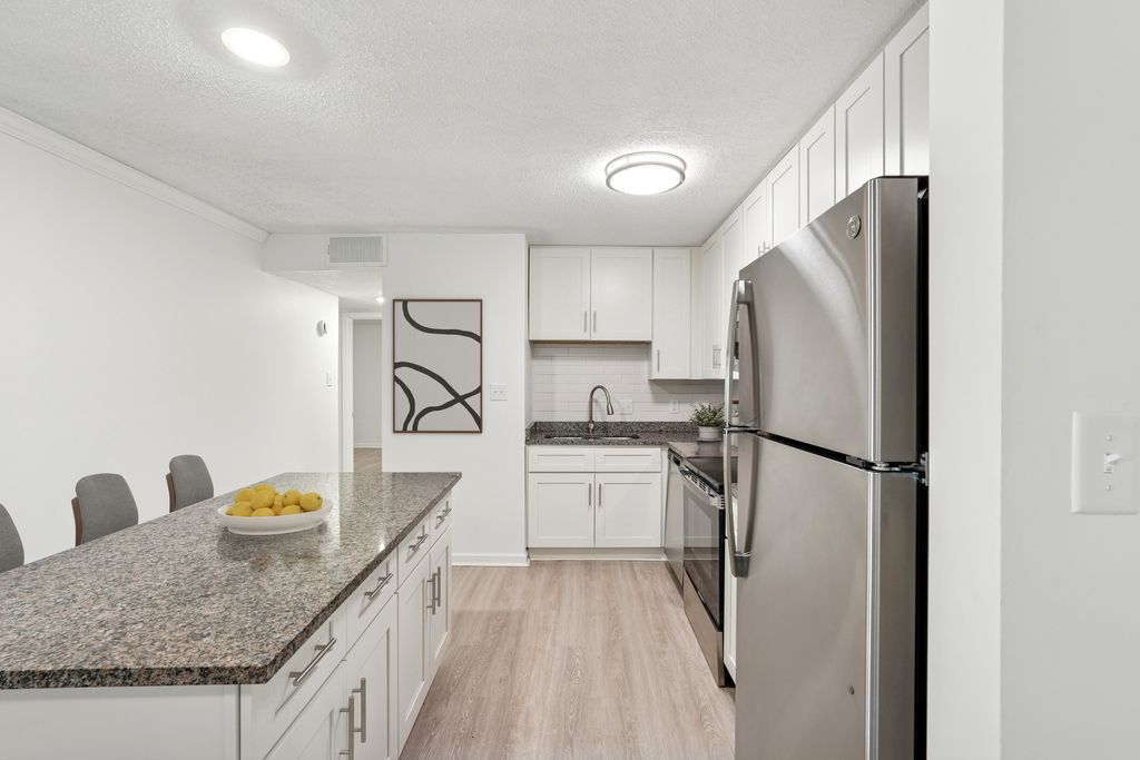 Modern kitchen with granite countertops, sleek stainless-steel appliances, and elegant white cabinetry, perfect for culinary enthusiasts.